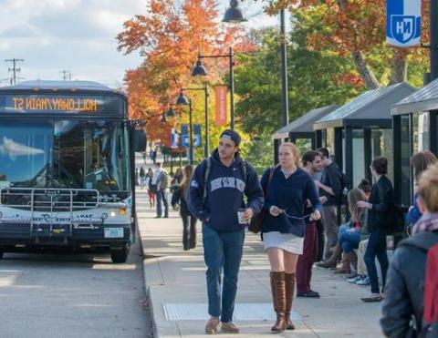 Wildcat Transit bus pulled up to Main Street Durham bus stop; students walking on sidewalk.