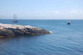 背景是一艘船和一艘帆船，沿着海洋的岩石海岸线.